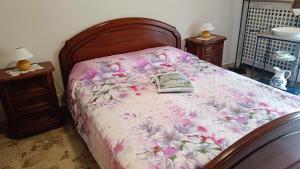 łóżko z różowym kocem z książką w obiekcie La Magnolia B&B w mieście Gassino Torinese