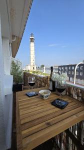 a table on a balcony with a lighthouse in the background at TheWatchtower plage dragon ferry à proximité in Calais