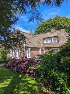 a large brick house with flowers in the yard at Das-Kommandeur-Haus-Ihr-Familien-Ferienhaus-in-Nieblum-auf-Foehr in Nieblum