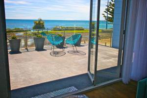 a balcony with two chairs and a view of the ocean at Penguin Beachfront Apartments in Penguin