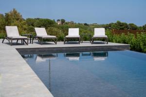 a group of chairs sitting next to a swimming pool at MòN Luxury Rooms SPA in Nicolosi