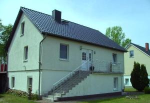 una grande casa bianca con scale sul lato di FeWo Alt Bukow nahe Ostseebad Rerik ad Alt Bukow