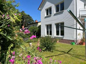 a house with pink flowers in the yard at M9 Ferienwohnung mit Balkon am Waldrand im Ostseeland in Neubukow