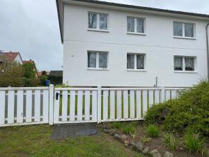 a white fence in front of a white house at M9 Ferienwohnung mit Balkon am Waldrand im Ostseeland in Neubukow