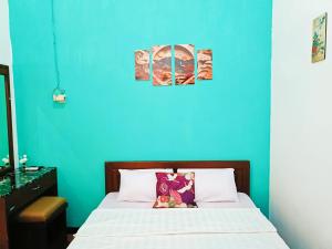 a bedroom with a blue wall and a bed at YUTAKA INN Stasiun Kota Madiun in Madiun +7 photos