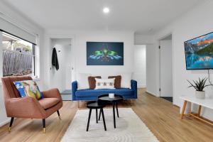 a living room with a blue couch and a chair at Bee at Scenic I 2 BR Apartment near Geelong CBD in Geelong