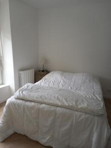 an unmade bed in a white bedroom at Plat Gousset in Granville