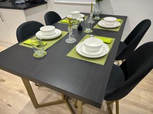 a black dining room table with black chairs and white dishes at Midland Apartments - Luxury Large Entire Unit Sleeps 4 in Luton +11 photos