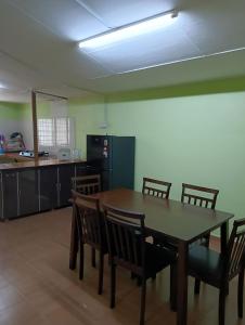 a dining room with a table and chairs and a kitchen at Impian Jaya Homestay in Macang +4 photos