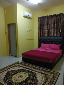 a bedroom with a bed with purple sheets and a rug at Impian Jaya Homestay in Macang