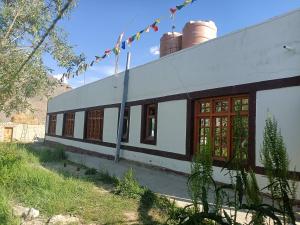 a white and black building with windows and flags at Padmaling guest house zanskar eco camp in Padam