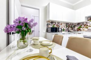 eine weiße Küche mit einem Tisch mit lila Blumen in einer Vase in der Unterkunft Business Class Residential complex EXPO Boulevard in Astana + 10 Fotos
