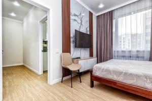 ein Schlafzimmer mit einem Bett, einem Schreibtisch und einem Fernseher in der Unterkunft Business Class Residential complex EXPO Boulevard in Astana