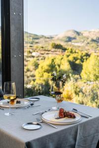 una mesa con platos de comida y copas de vino en VIVOOD Landscape Hotel & Spa - Designed for Adults, en Benimantell