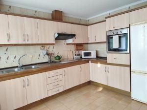 a kitchen with wooden cabinets and a sink and a microwave at Piso de Alba in Chantada