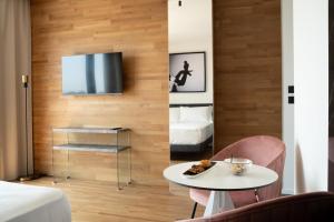 a room with a table and a tv on a wall at MòN Luxury Rooms SPA in Nicolosi