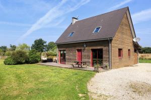 eine Scheune mit einer roten Tür auf einem Grasfeld in der Unterkunft La Maison Merlin - Maison avec piscine Sénoville in Senoville