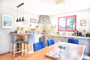 eine Küche mit einem Holztisch und blauen Stühlen in der Unterkunft La Maison Merlin - Maison avec piscine Sénoville in Senoville + 7 Fotos