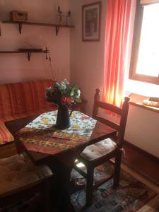 una stanza con un tavolo e un vaso con dei fiori di Grangia in borgo antico a Bardonecchia Altre 41 foto