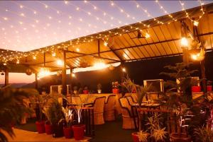 a patio with tables and chairs and lights and plants at Hotel Hallmark in Alwar