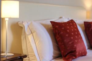 a bed with red and white pillows and a lamp at Villa Maria Luigia in San Biagio di Callalta
