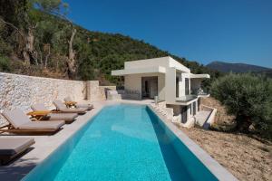 a swimming pool with lounge chairs and a house at Villa Eptanisa in Sivota