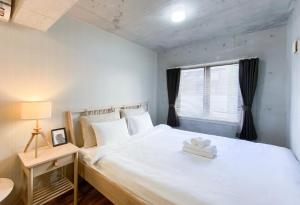 a bedroom with a large white bed and a window at Uhome Otsuka Villa in Tokyo
