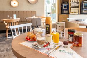 a table with a plate of food and orange juice at Brit Hotel Orléans St Jean de Braye - L'Antarès in Saint-Jean-de-Braye