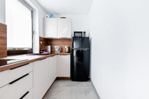 a black refrigerator in a kitchen with white cabinets at Agroturystyka u Janosika 1 in Bozkow