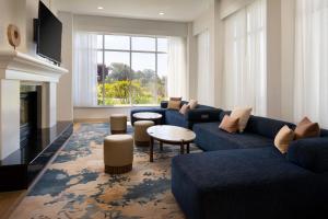 a living room with blue couches and a fireplace at Courtyard San Francisco Airport Burlingame in Burlingame