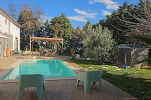 a swimming pool with two chairs next to a yard at Hébergement - Canal du midi in Saint-Martin-Lalande