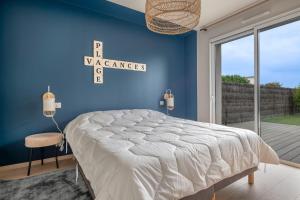 a bedroom with a bed and a blue wall at à 700m du port de Piriac, maison neuve pour 7 in Piriac-sur-Mer