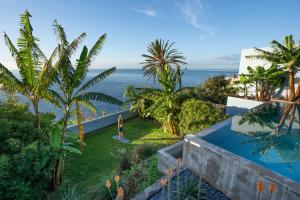 una donna è in piedi sull'erba accanto a una piscina di Pirate House Sea front Private Pool Garden Funchal a Funchal