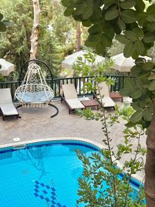 a pool with a swing and chairs next to a tree at Symbola Oludeniz Beach Hotel in Oludeniz