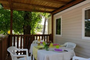 stół i krzesła na tylnej werandzie domu w obiekcie Happy Camp mobile homes in Camping Villaggio Lamaforca w mieście Carovigno