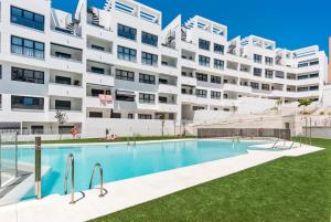 a swimming pool in front of a large apartment building at Casa Los Vecinos - Luxury Rooftop Penthouse in Estepona