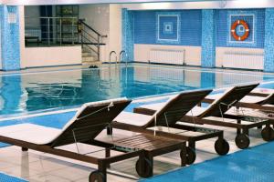 a swimming pool with two lounge chairs in it at Belon Life Hotel in Astana