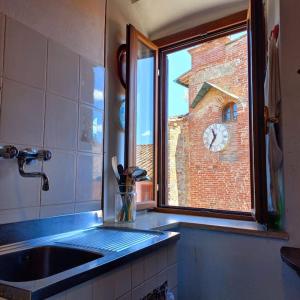 a kitchen with a sink and a window with a clock tower at La Casa del Gallo in Radicondoli