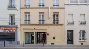 a building with doors and windows on a street at Hotel la Perle Montparnasse in Paris