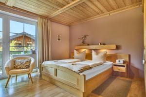 a bedroom with a bed and a chair and a window at Haus Wiesengrund in Frauenau