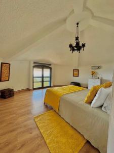 a bedroom with a large bed and a chandelier at O Moinho de Vale da Mó in Anadia