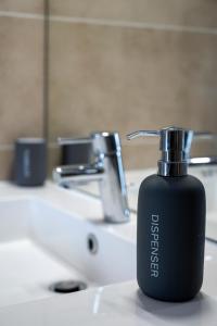 パリにあるLOFT Paris la Villetteの- バスルームの洗面台に座る黒いボトル入り石鹸