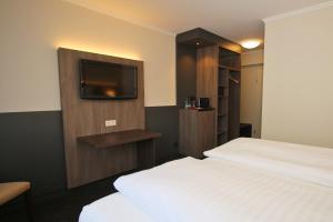 a hotel room with a bed and a flat screen tv at Hotel Graf Balduin in Esterwegen +40 photos