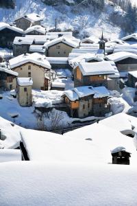 ein schneebedecktes Dorf mit Häusern und einer Kirche in der Unterkunft Chez Michel in Sainte-Foy-Tarentaise