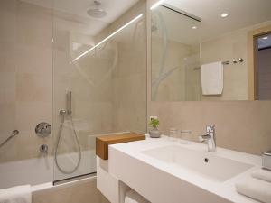a white bathroom with a sink and a shower at Hotel Kompas in Dubrovnik