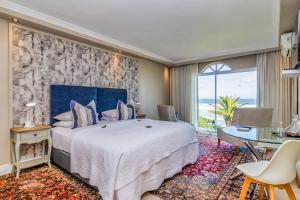 a hotel room with a large bed and a table at Hermanus Beachfront Lodge in Hermanus
