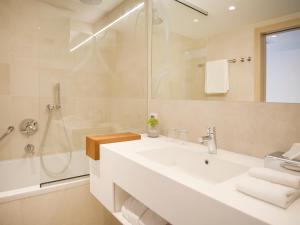 a white bathroom with a sink and a shower at Hotel Kompas in Dubrovnik