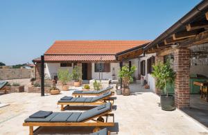 a patio with chaise lounges and a building at Villa Rustica ZadarVillas in Smilčić