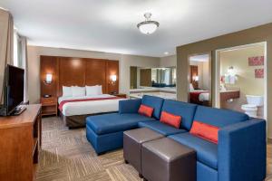 a hotel room with a bed and a blue couch at Comfort Suites Urbana Champaign, University Area in Champaign