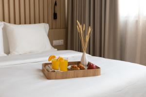 bandeja de fruta y zumo de naranja en una cama en Eria Suites Thessaloniki, en Tesalónica 97 fotos más